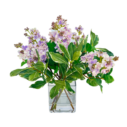 Lilac flower arrangement with green foliage in a square glass vase, 15 inches high