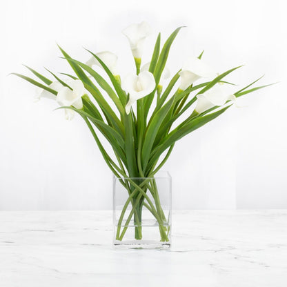 White calla lily arrangement in a clear glass vase with acrylic water, 15 inches high